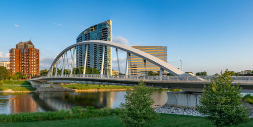 Bridge over river by buildings against sky in city