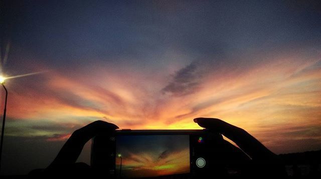 sunset, silhouette, orange color, sky, part of, cloud - sky, cropped, transportation, cloud, sun, low angle view, person, mode of transport, sunlight, outdoors, glass - material, unrecognizable person, nature