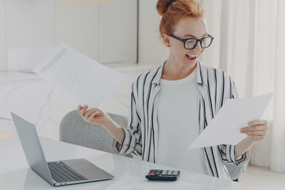 Midsection of woman using mobile phone while sitting on table