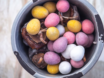 Easter sweets, multicolored chocolate eggs and dried persimmon in a gray ceramic jar 