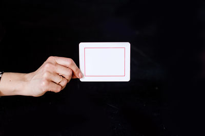 Cropped hand of person using digital tablet against black background