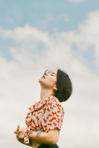 Side view of woman looking up against sky