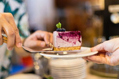 Cropped hands of friends having dessert at table