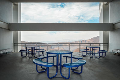 Brutalist concrete architecture, large space overlooking a ravine, blue dining benches. beam