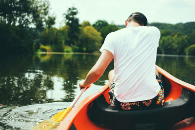 Rear view of man on boat against lake