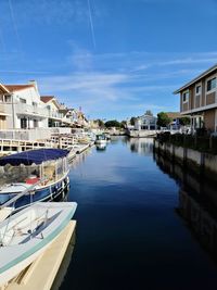 Sailboats moored on canal by buildings against sky in city