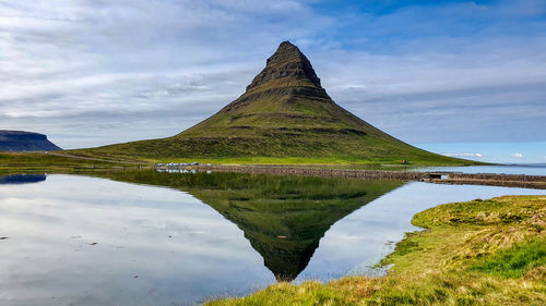 Scenic view of kirkjufell mountain reflected in a lake against sky