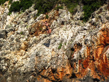 Low angle view of mid adult woman jumping against rock formations