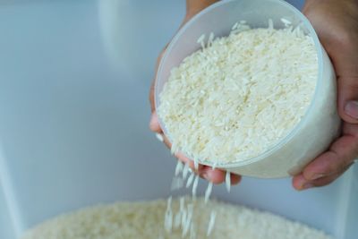 Cropped hands spilling rice from bowl