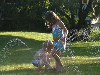 Siblings by spraying water in park