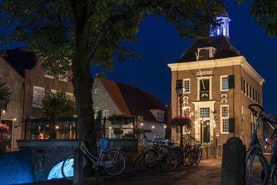 Bicycle by building against sky at night