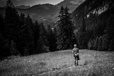 Rear view of woman walking on landscape leading towards mountain