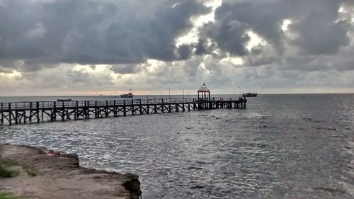 Pier on sea against cloudy sky