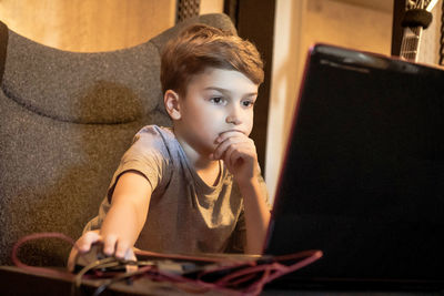 Portrait of cute boy looking away while sitting at home