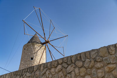 Low angle view of electricity pylon against clear blue sky