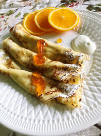 Beautifully served thin pancakes with orange jam and oranges