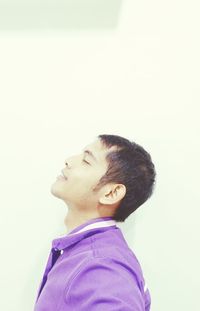 Portrait of young man looking away against white background