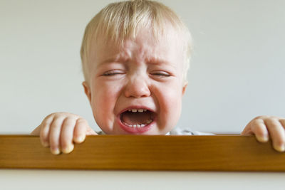 Close-up of baby boy screaming while crying in crib at home