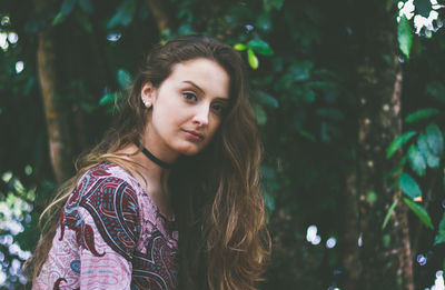 Portrait of smiling young woman standing against trees