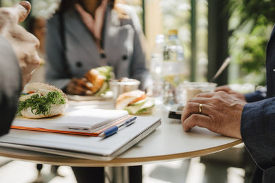 Businesswoman with businessman standing at table while having food during networking event at convention center