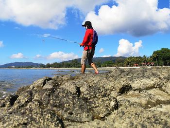 Full length of man standing on rock against sky