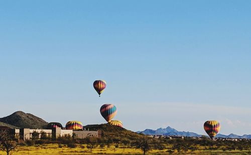 Hot air balloon flying over mountains against clear blue sky