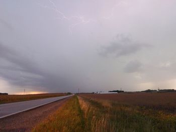 Road amidst field against sky