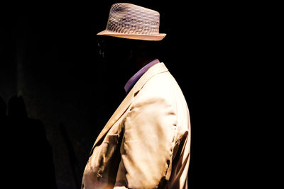 Side view of man with invisible face against black background
