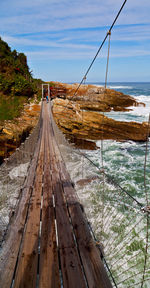 Footpath leading towards sea against sky