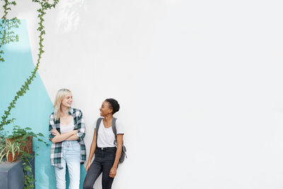 Smiling female friends against wall