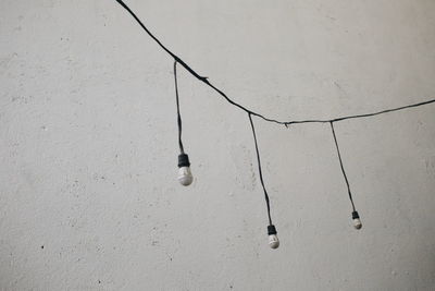 Low angle view of light bulbs hanging on wall