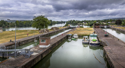 High angle view of river amidst trees against sky. boats parked