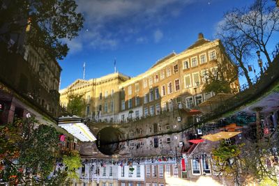 Buildings by canal against sky in city