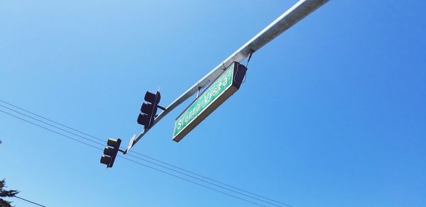 Low angle view of information sign and road signal on pole against clear blue sky