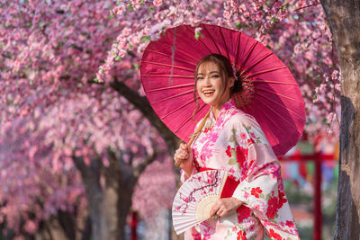 Close-up of woman holding pink cherry blossom