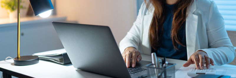 Midsection of woman using laptop at office