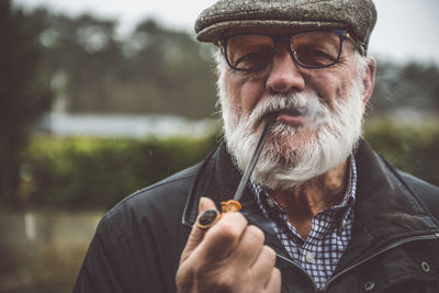 Portrait of senior man smoking at park