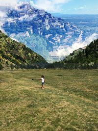 Rear view of woman on field against mountains