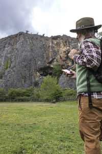 Male adventurer backpacker using smart phone on top of a valley