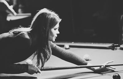 Side view of woman playing pool