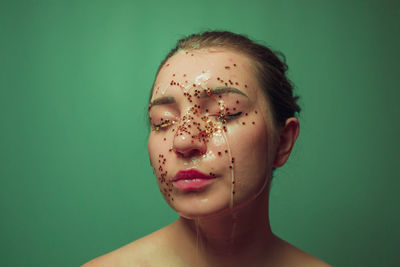 Close-up of woman with water and star shape decoration against green background