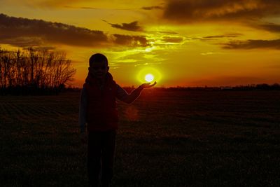 Man standing on field against sky during sunset