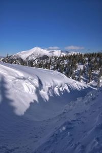 Snow covered mountain against blue sky