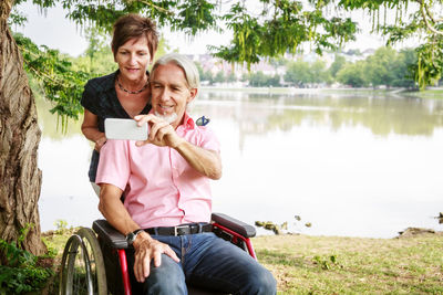 Portrait of a smiling young couple sitting on lake