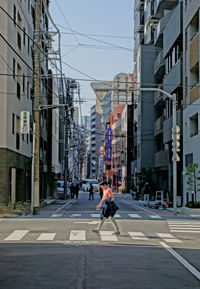 Man walking on city street against buildings