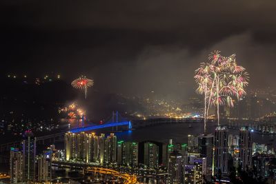Illuminated fireworks over cityscape against sky at night