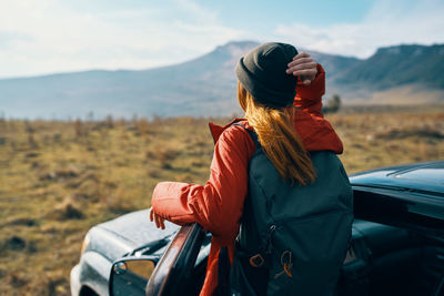Rear view of woman standing on car against mountain