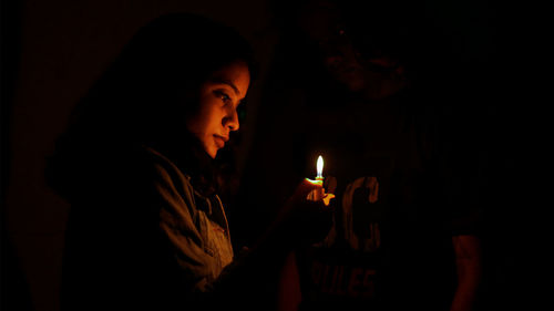 Silhouette woman holding burning candle