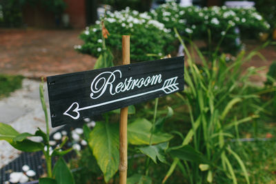 Close up of a restroom direction sign during an outdoor garden wedding