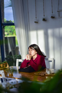 Young woman sitting on table at home